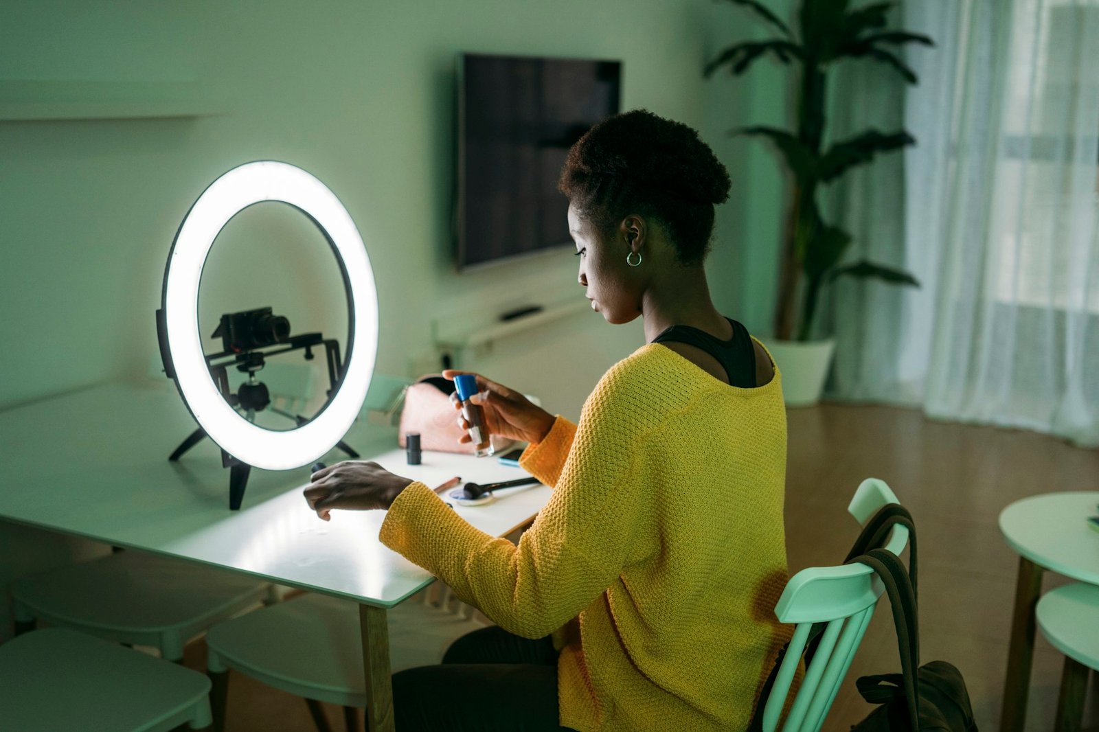 A woman is at home creating content with a ring light and a camera for her online audience